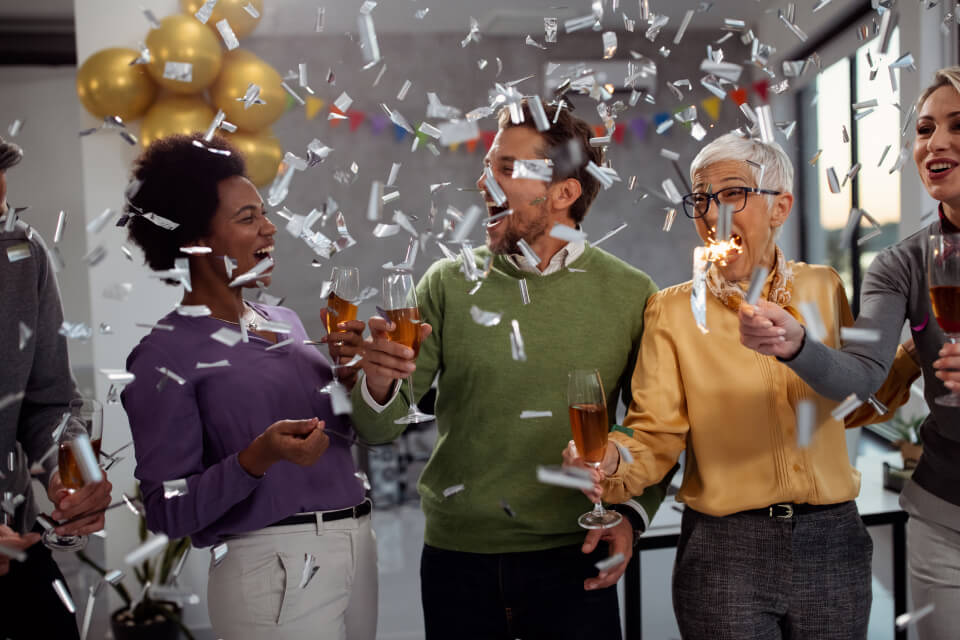 Employees cheering with drinks in their hands at a party
