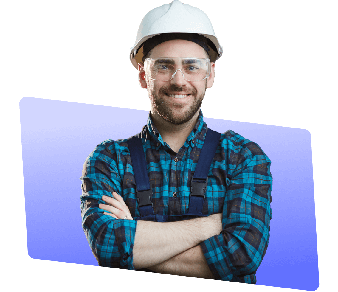 Smiling male employee wearing safety goggles and a white helmet with arms crossed