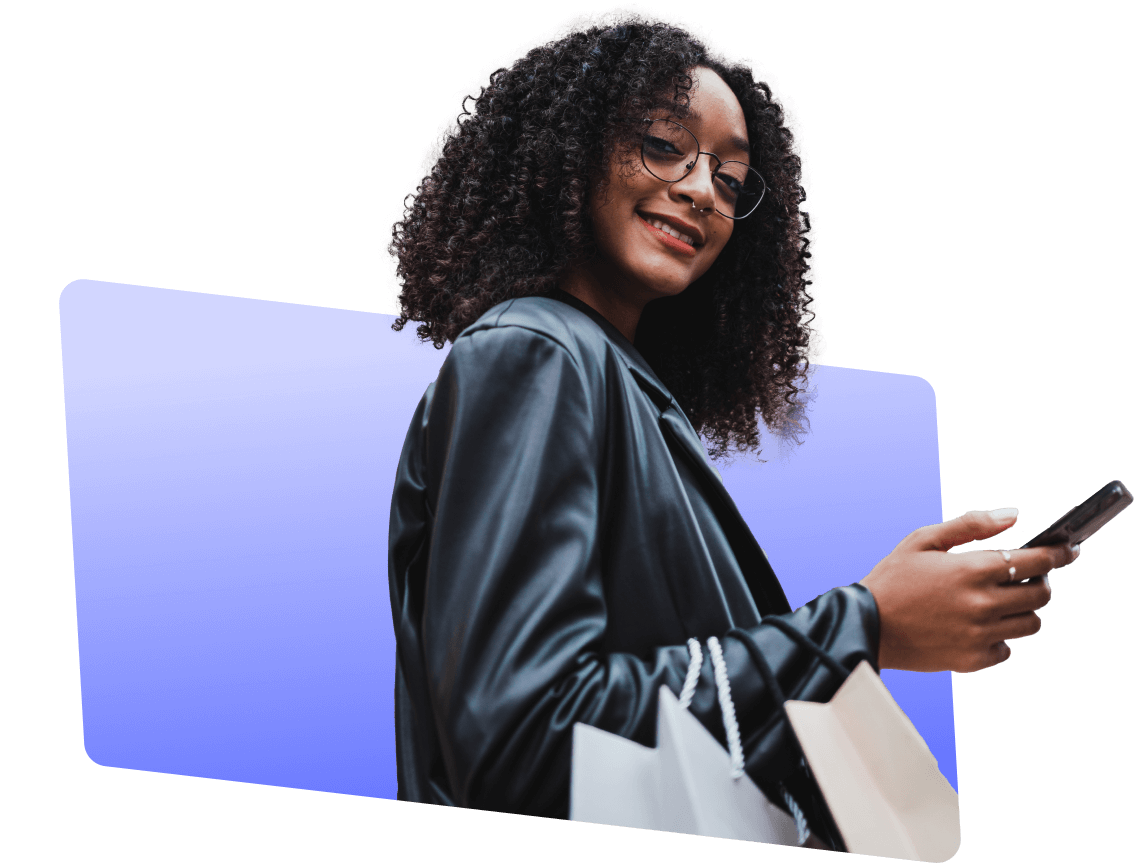 Smiling black female in a black leather jacket holding a phone, deciding between Walmart, Sony, Amazon, and Apple gift card